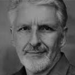 Sort-hvitt portrett av en eldre mann med lyst hår og skjegg, iført skjorte