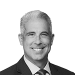 En svart-hvitt portrett av en mann i dress, smilende.