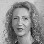 Et svart-hvitt portrett av en kvinne med krøllete, lyst hår, smilende mot kamera.