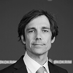 Svart-hvitt bilde av en mann med mørk dress og skjorte