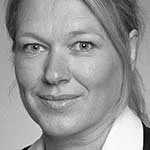 Portrett av en kvinne med lyst hår og smil, tatt i svart-hvitt.