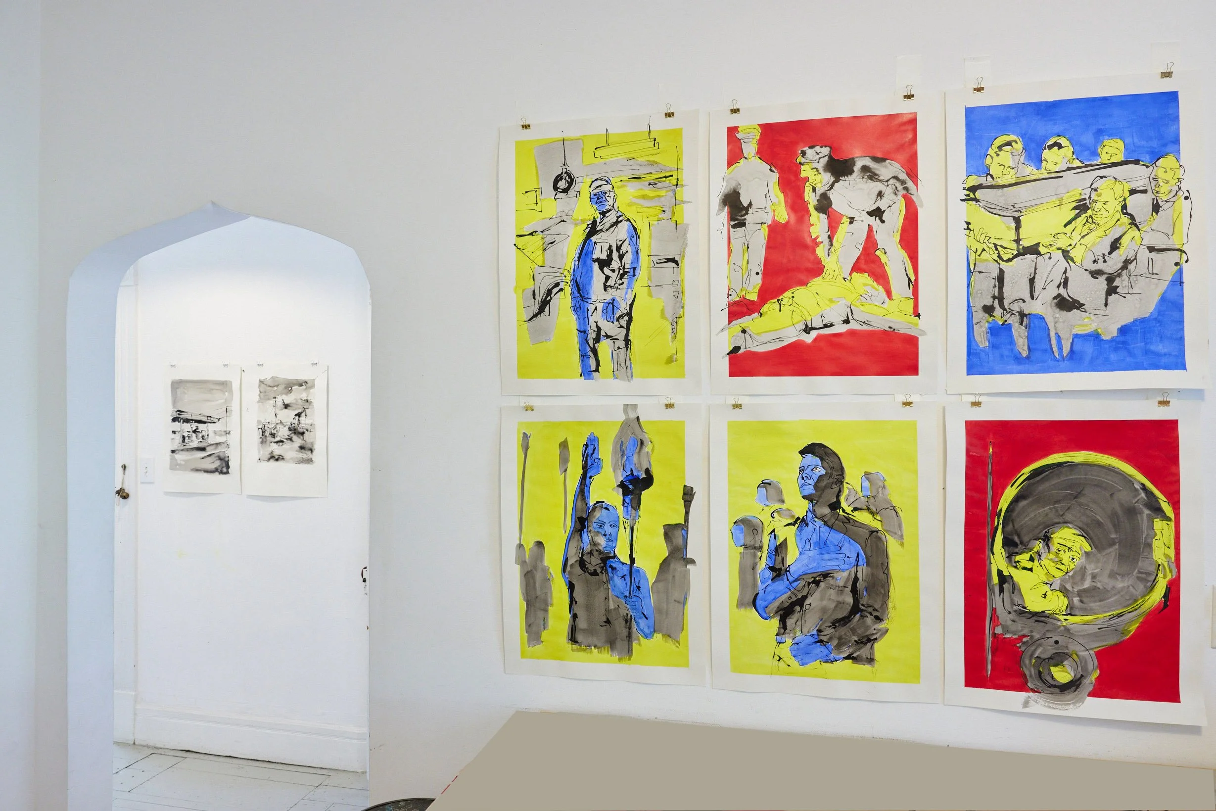 Art exhibit with six large, colorful paintings on a white gallery wall, depicting various figures and scenes with bold black outlines and backgrounds in yellow, red, and blue.