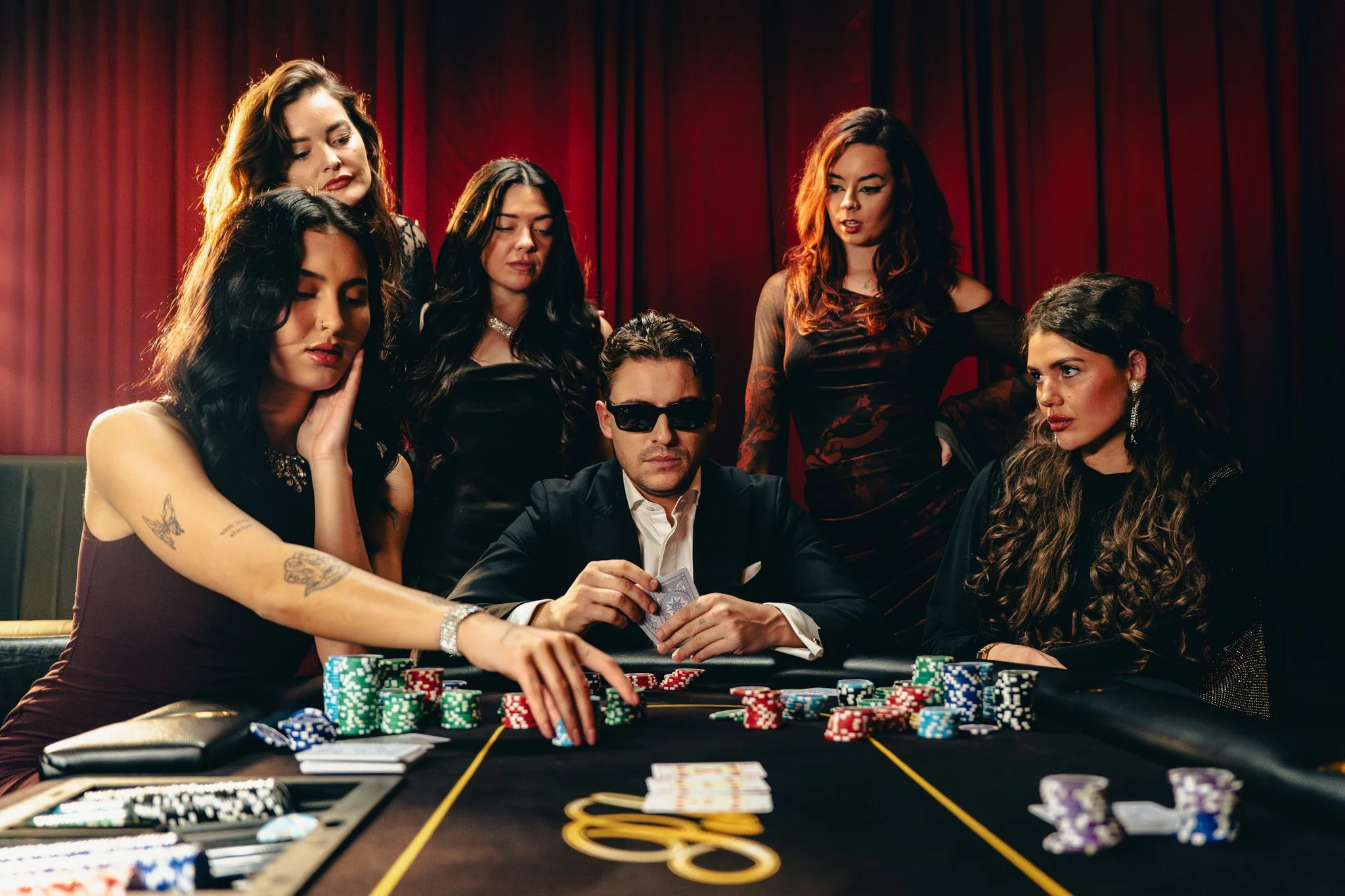 Dutch rapper Lil Kleine at a poker game, sitting around a table with chips and playing cards, in a room with red curtains.