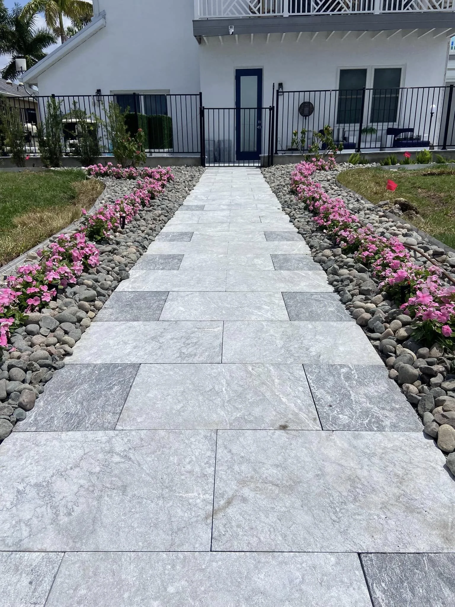 A paved walkway with gray stone tiles leading to a home in Port Charlotte Florida installed by LD Lifestyles.
