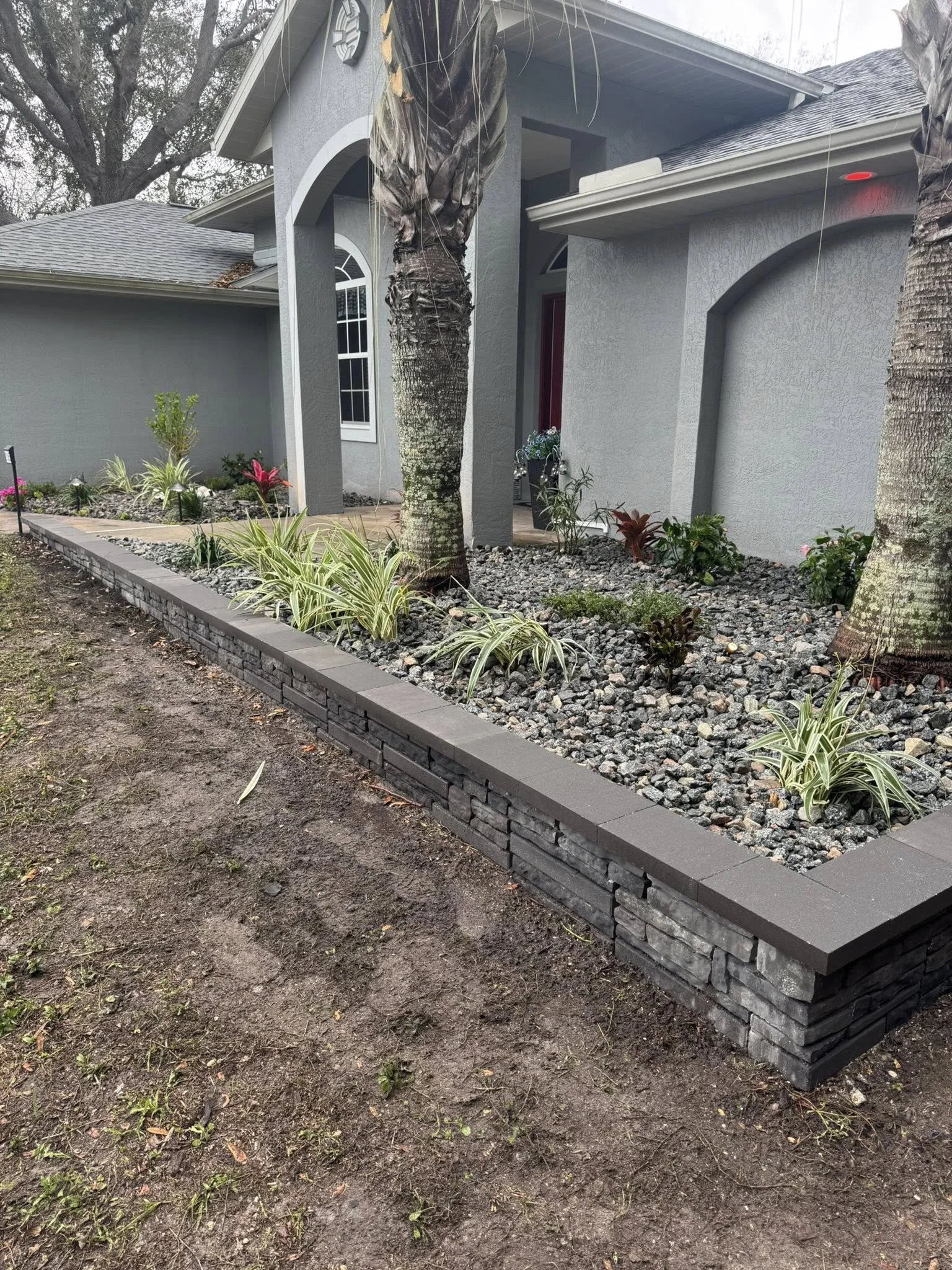 4 tier retention wall with cap, low voltage light system, plants and tree installation with Salt N Pepper Chips for base installed in Port Charlotte, FL.
