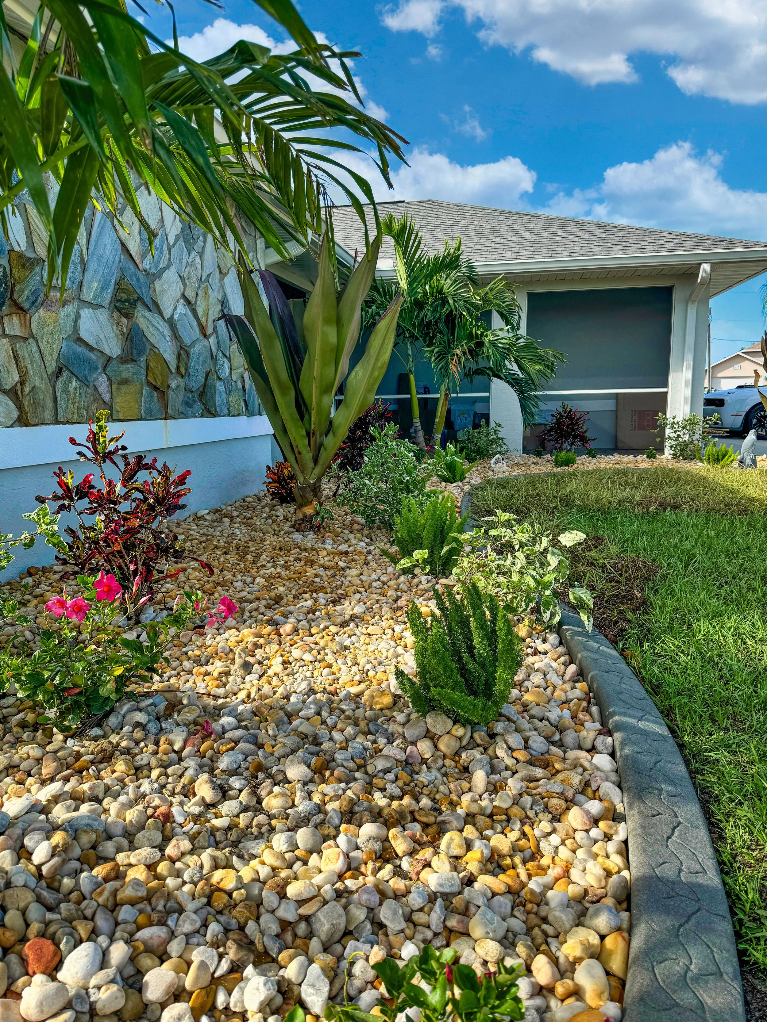 Port Charlotte home landscape designed by LD Lifestyles with rocks, concrete curbing, and plants.