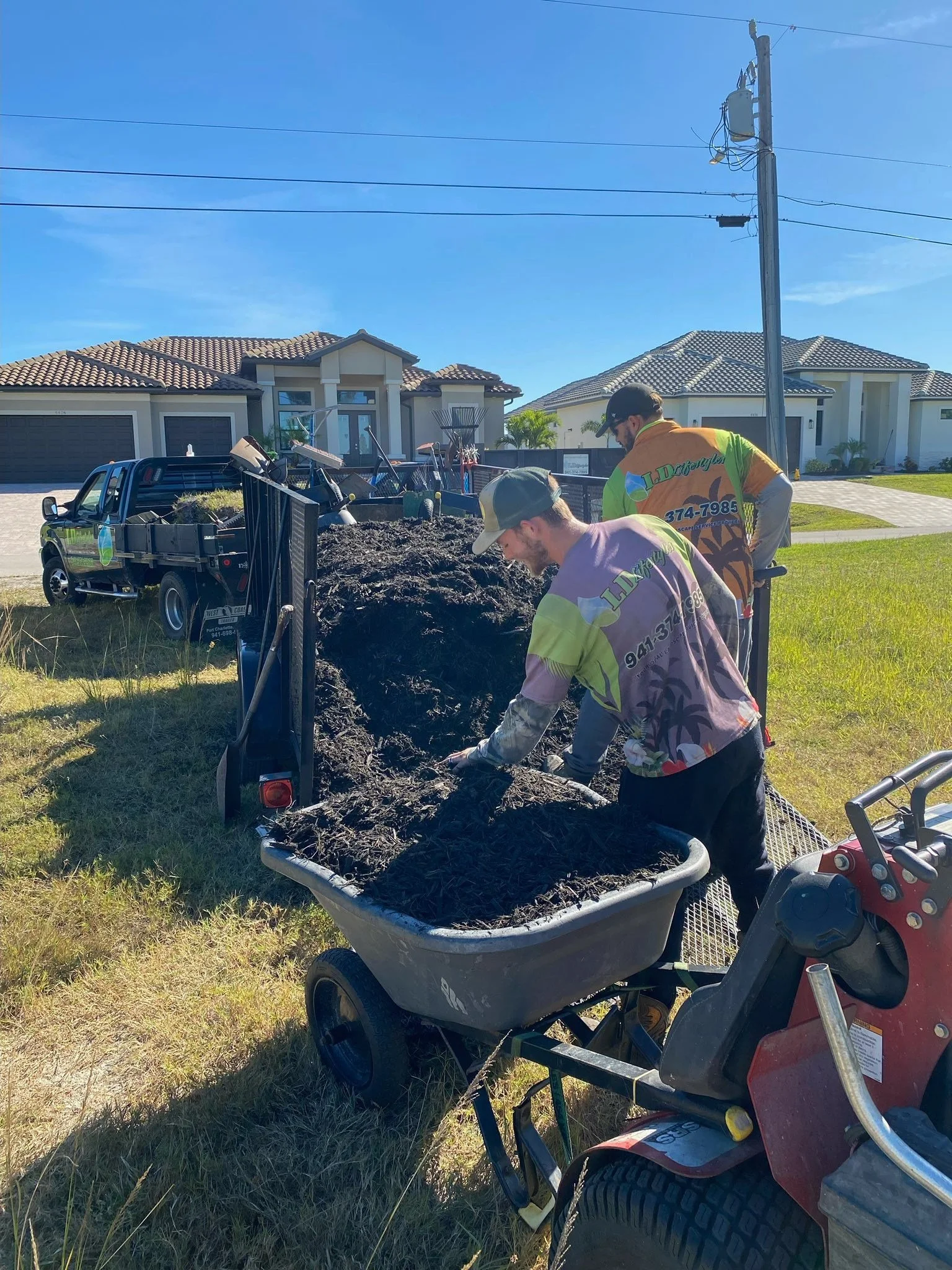 LD Lifestyles workers putting mulch inside wheelbarrows to install in landscape beds in Punta Gorda Florida.