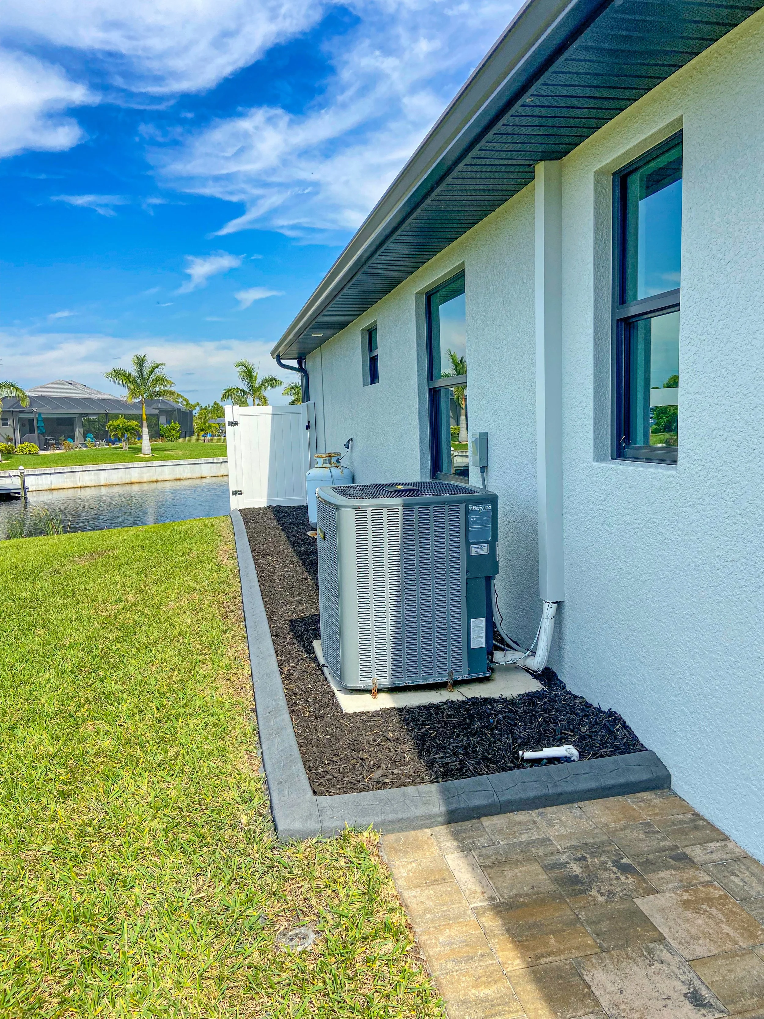 Concrete landscape curbing installed on the side of a home in Port Charlotte by LD Lifestyles.