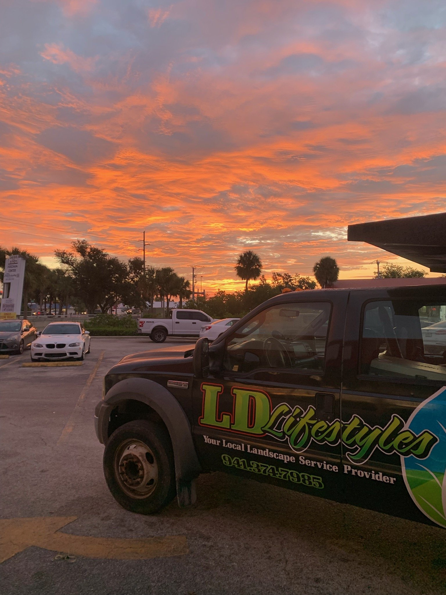 LD Lifestyles truck parked in parking lot during sunrise before performing landscaping services.