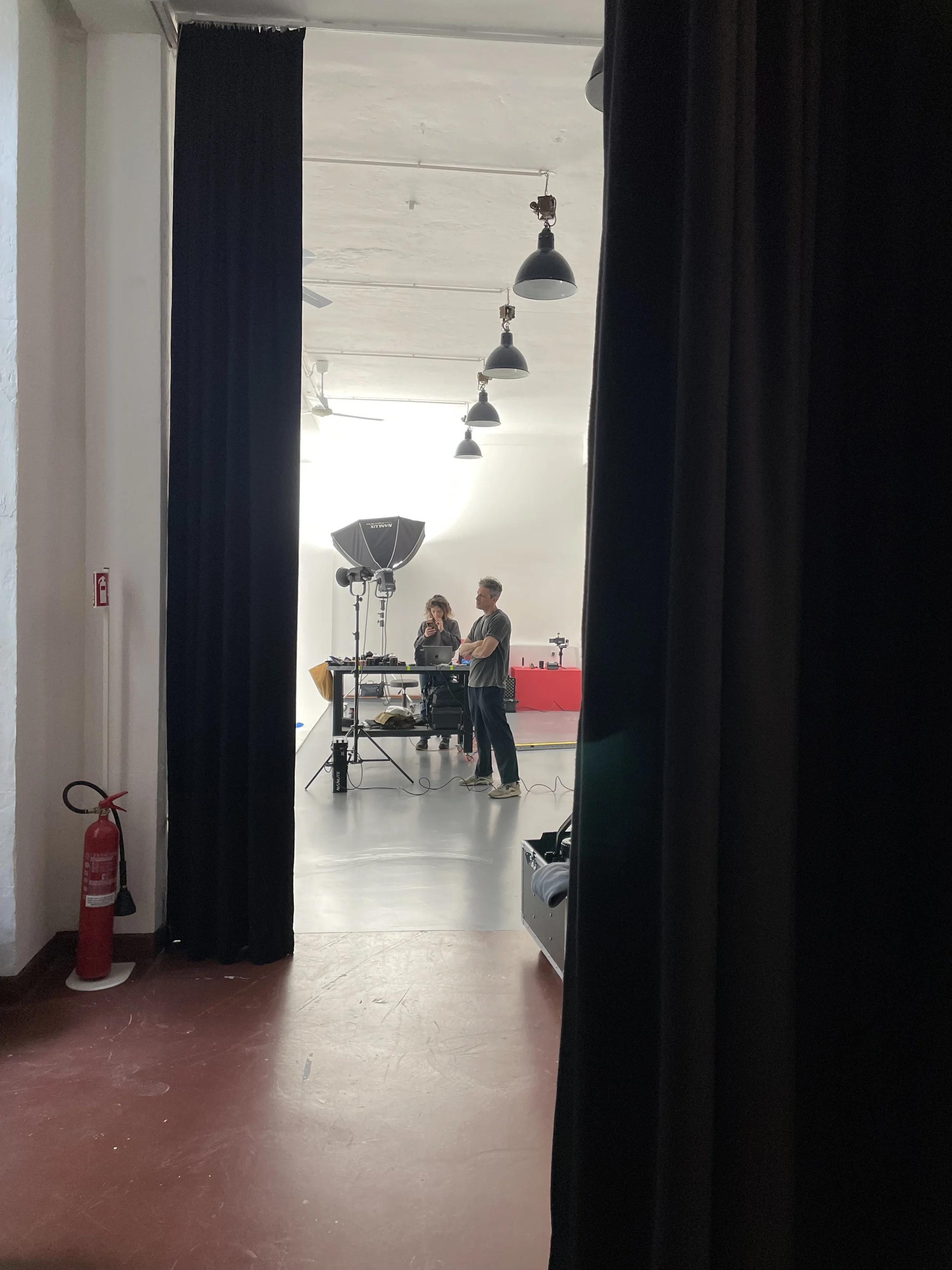 Persone in uno studio fotografico, con attrezzatura di illuminazione e un ricevitore di musica.