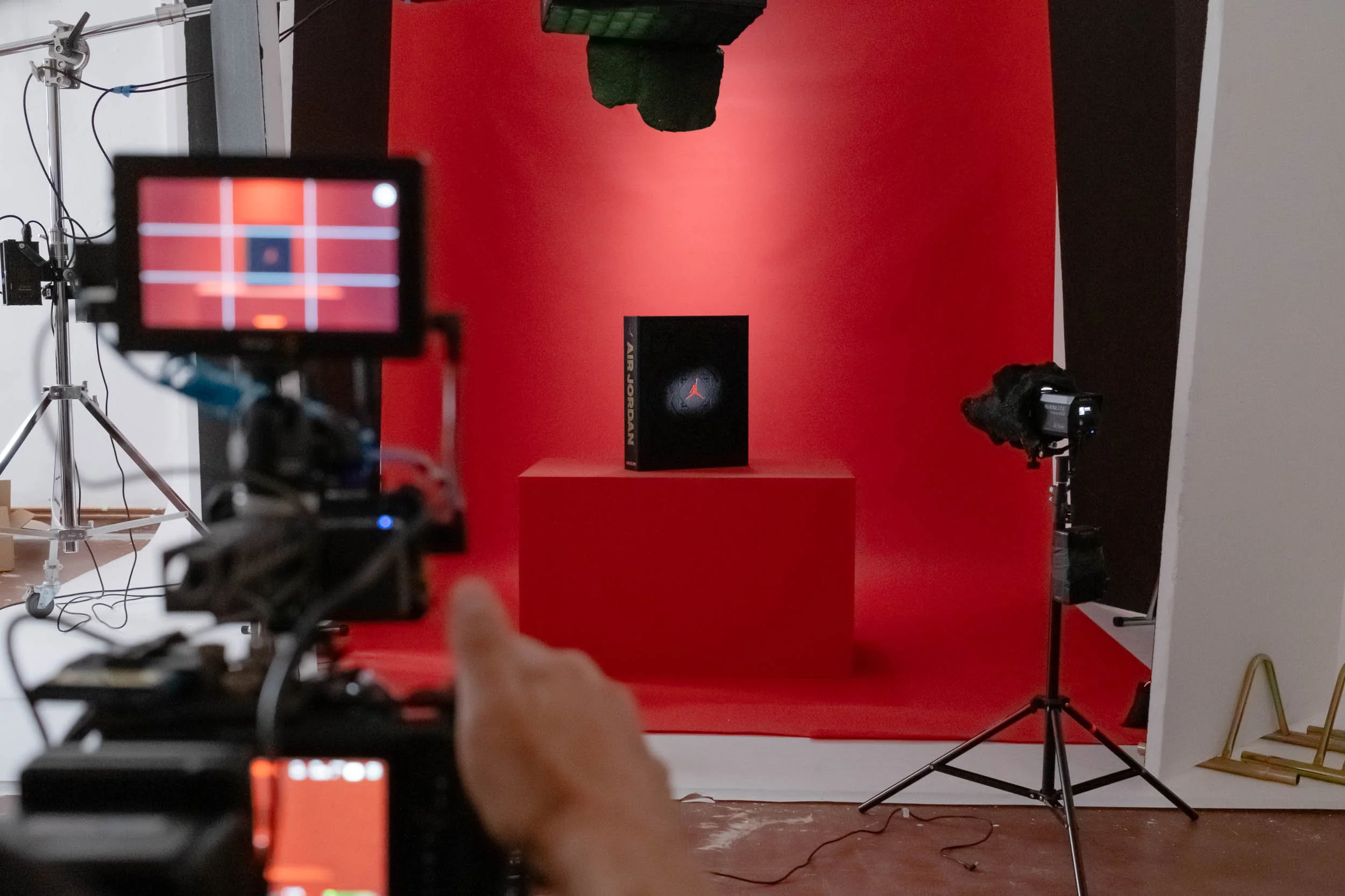 Stanza fotografica con sfondo rosso, pannello con logo Jumpman di Air Jordan, telecamere, luci e strumenti di ripresa
