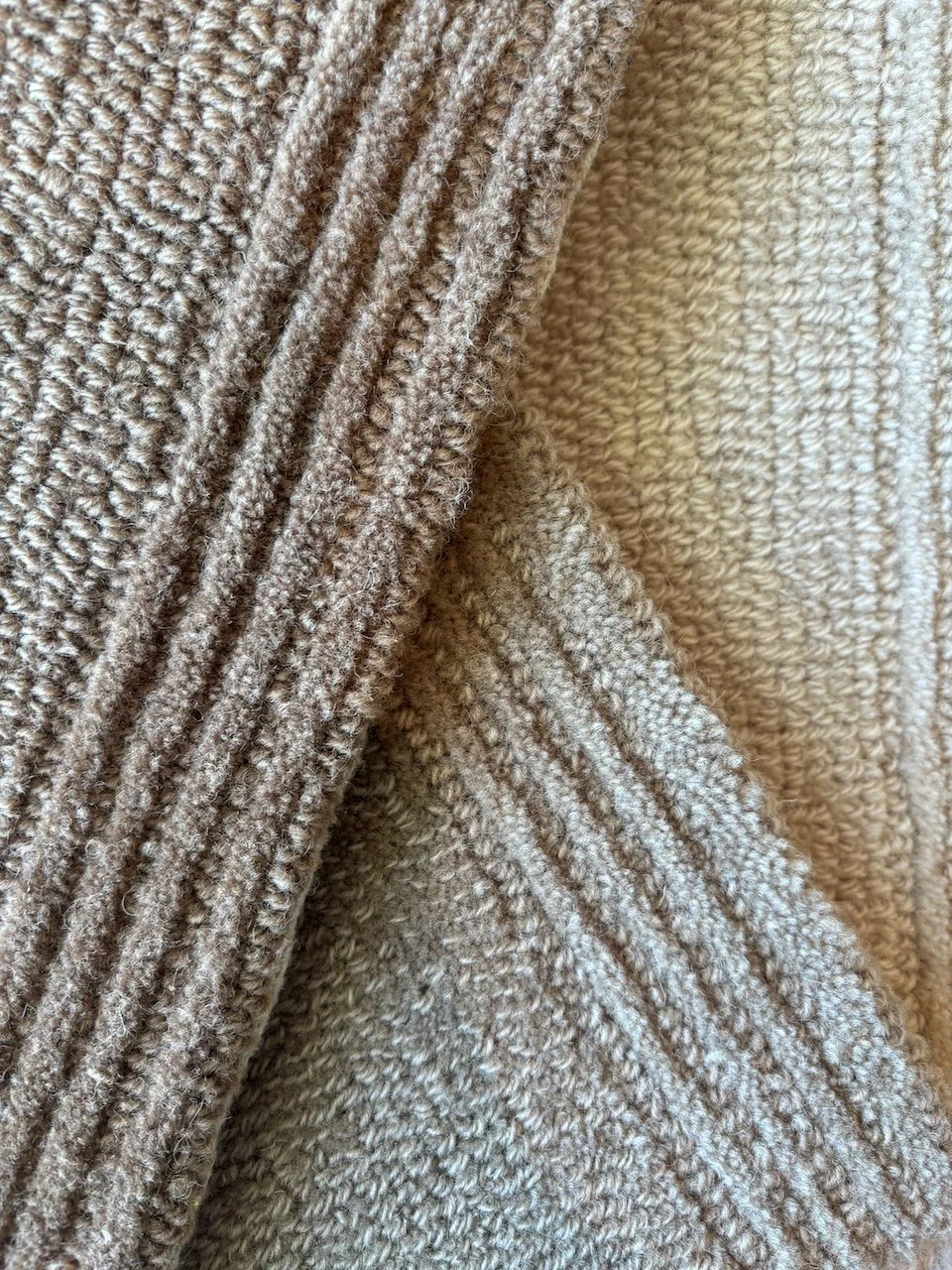 Tæt på beige- og lysebrune uldtæpper med forskellige strikkemønstre.