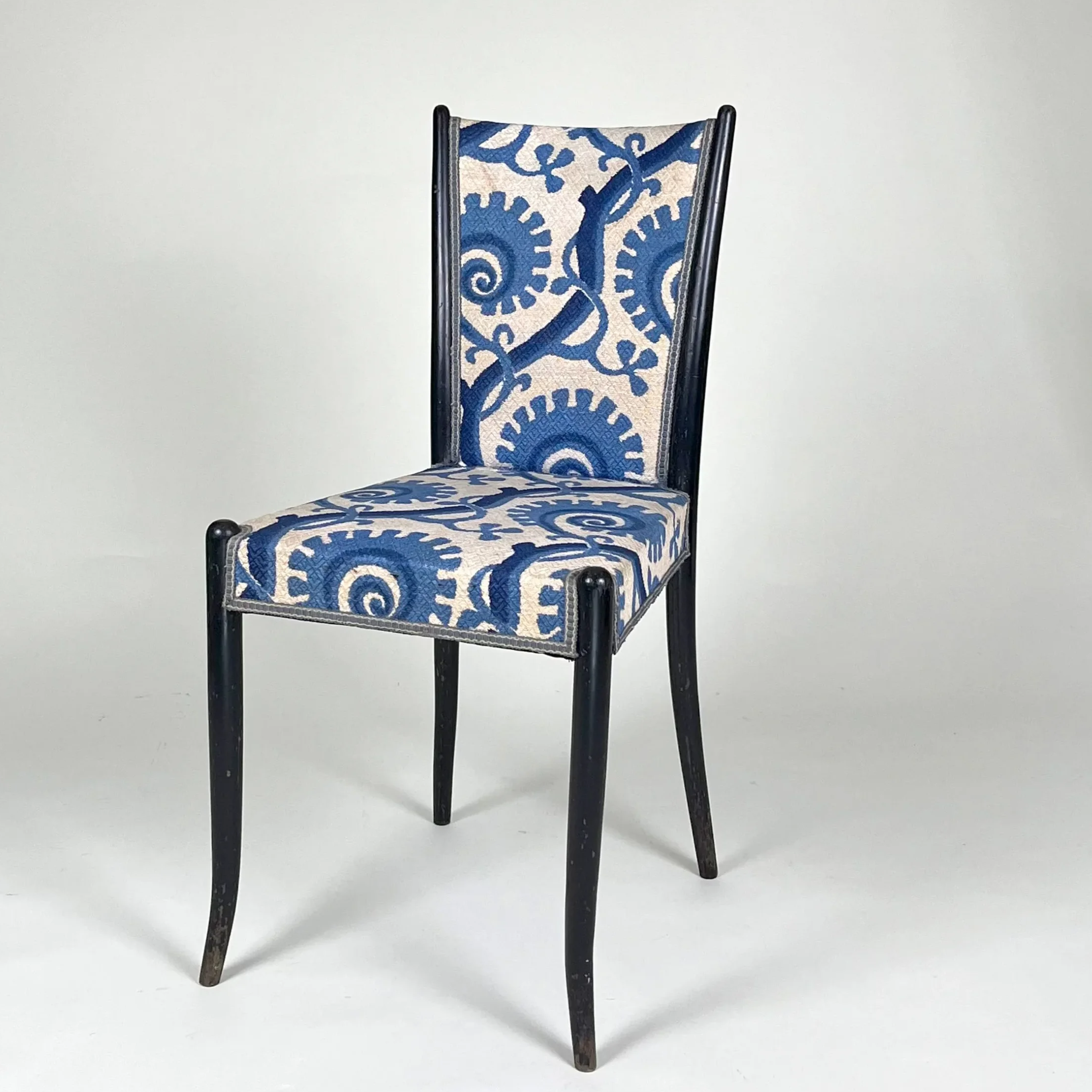 En sort træstol med blå og hvid mønstret polstring.