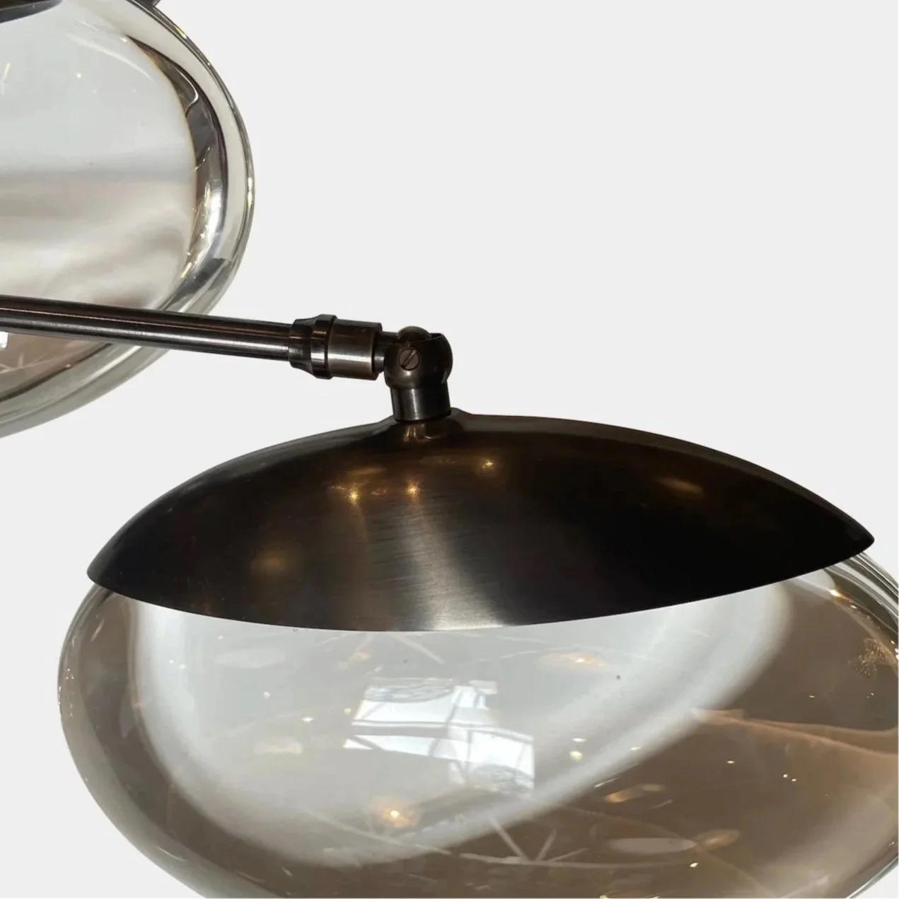 En moderne væglampe med en sort metal skærm, der lyser nedad, og to glasvaser med reflekterende overflader.