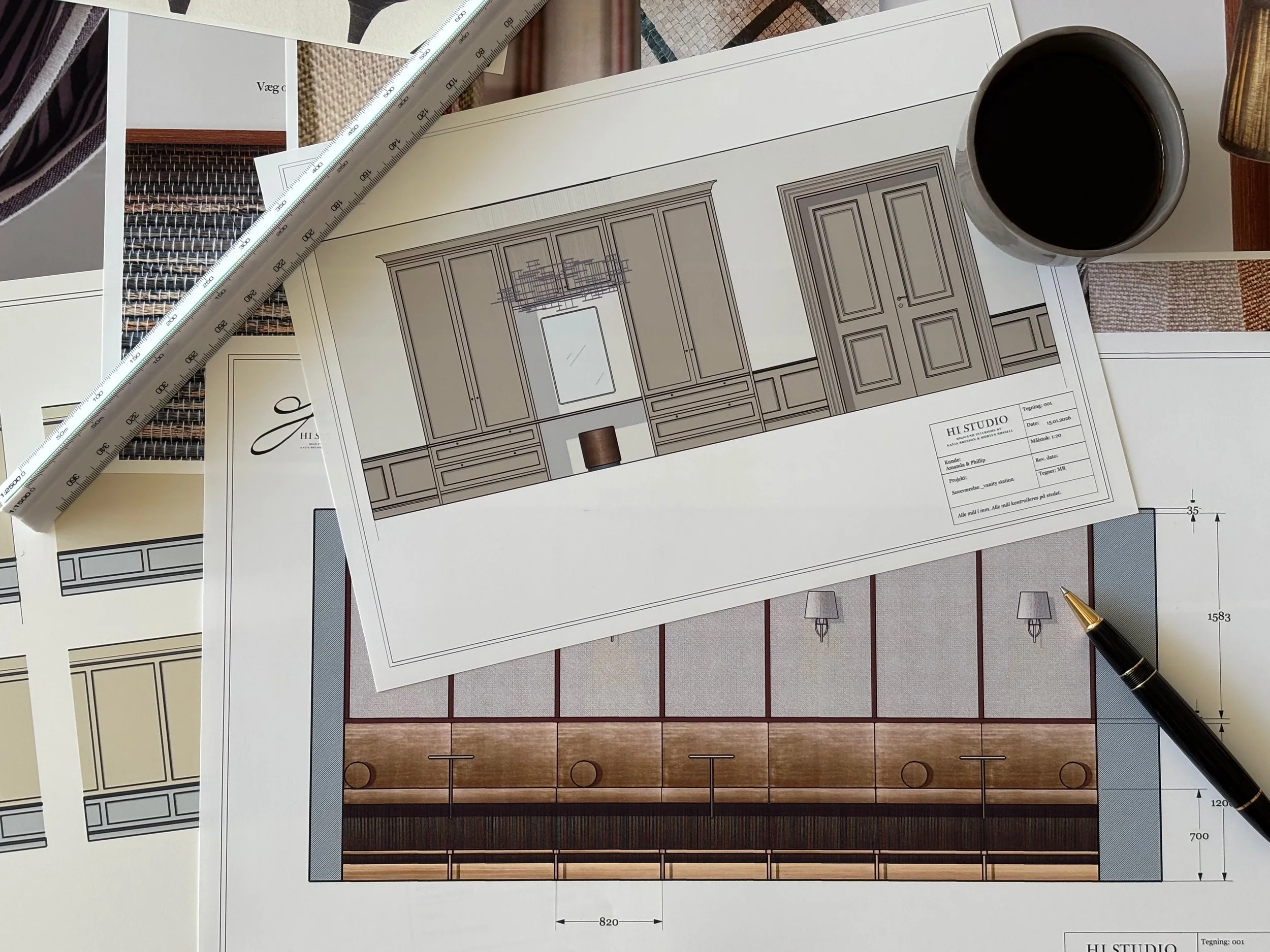 Arkitekttegning og mønstre af indretning, en kop kaffe, en sort boldpen, en måler, og flere arkitekttegninger.