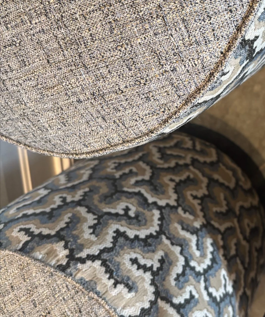 Nærbillede af to mønstrede stoffeklædte overflader, muligvis en stol og et andet møbel.