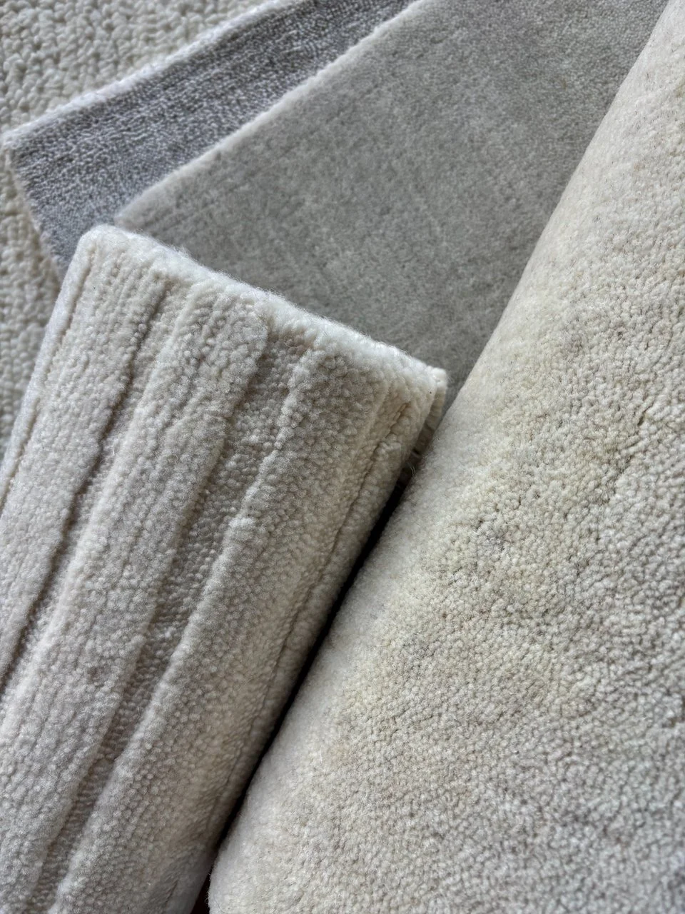 Nogle vaskede, hvide og grå håndklæder i forskellige størrelser og teksturer lagt sammen.