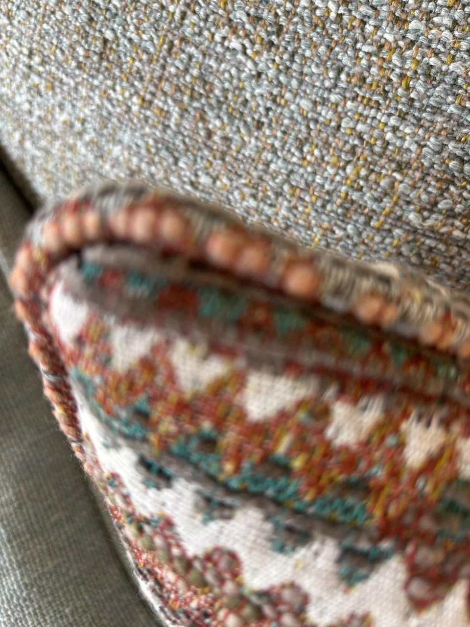 Tæppe med farverige mønstre og et tekstilfremstillet stykke, det er tæt på kameraet og lidt uklart.