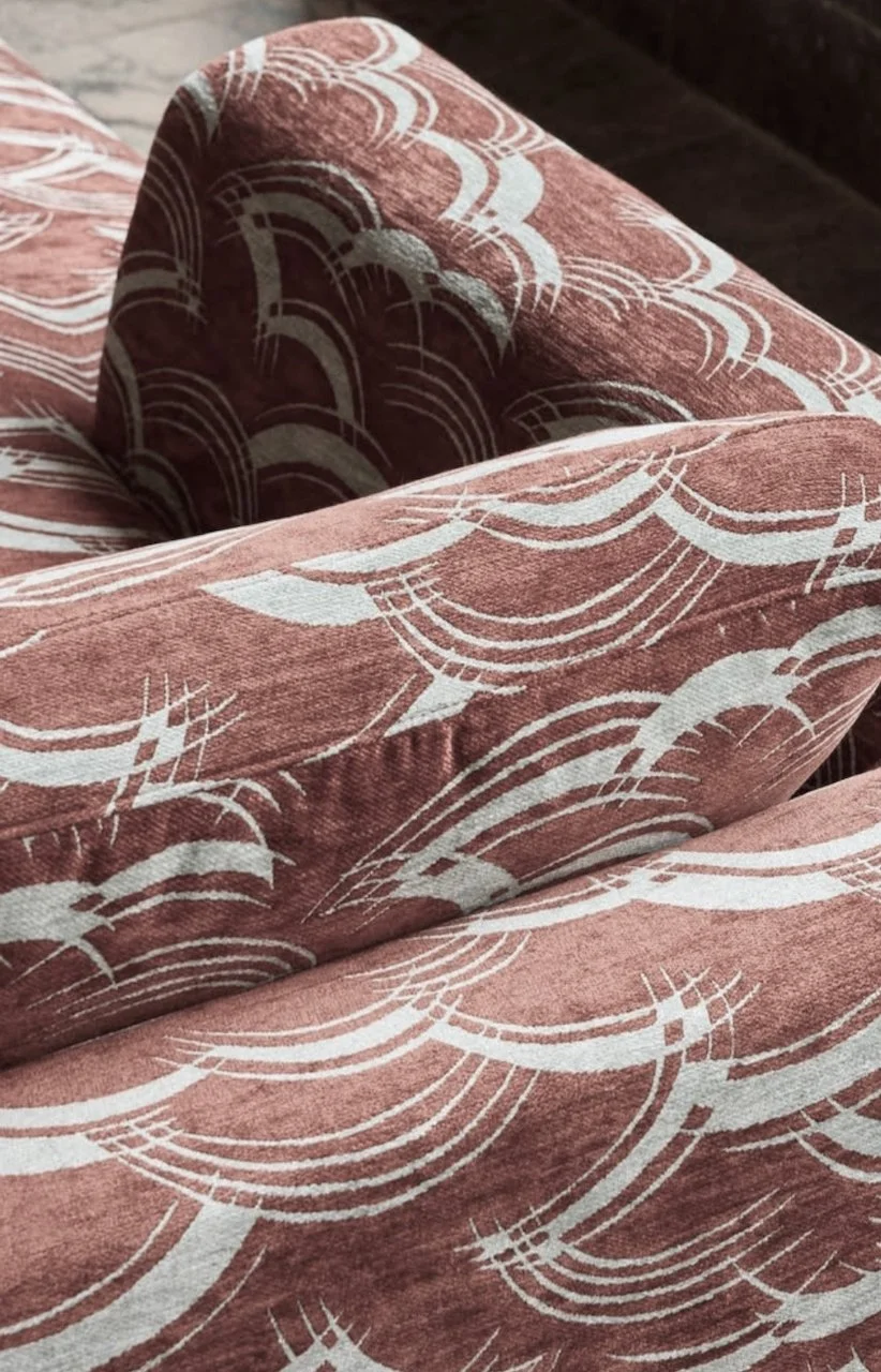 Et møbel eller tekstil med lyserøde og hvide geometriske mønstre, formodentlig en sofa eller en pude.