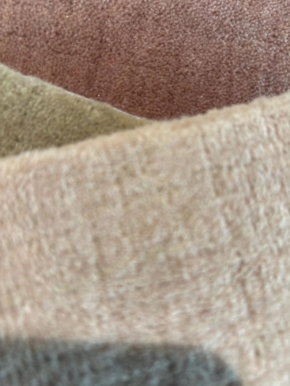 Nærbillede af flere lag af forskellige stofteksturer i brune, beige og grå nuancer.