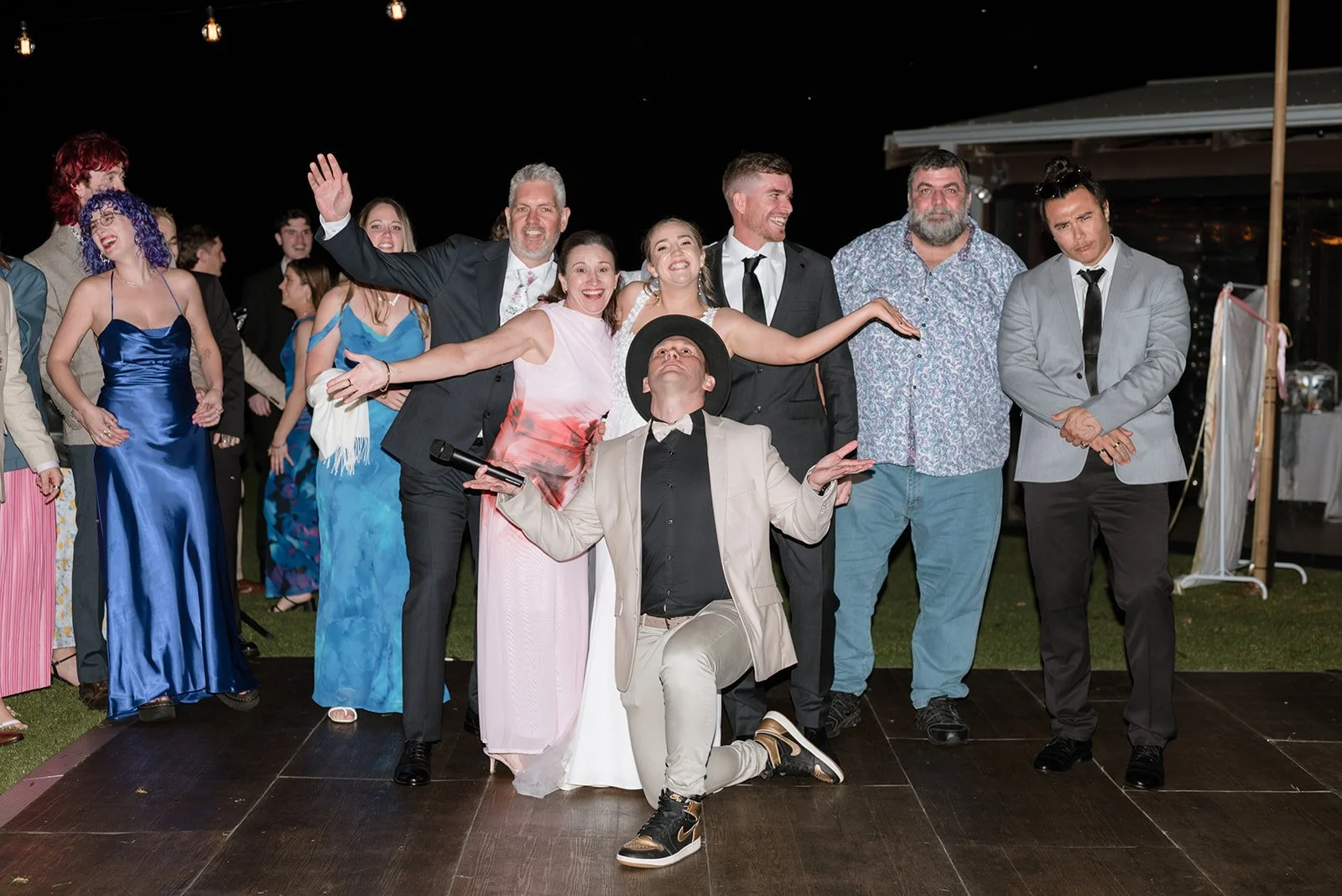 Group of people at a celebration or party, posing on a dance floor at night, with festive attire and a joyful atmosphere.