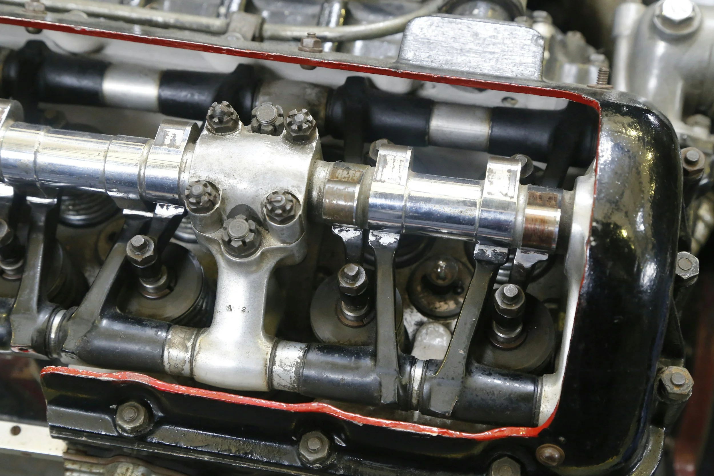 Close-up of an internal car engine with visible camshaft, bolts, and other mechanical parts.