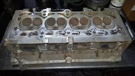 A used engine cylinder head with visible valves and valve springs on a workbench.
