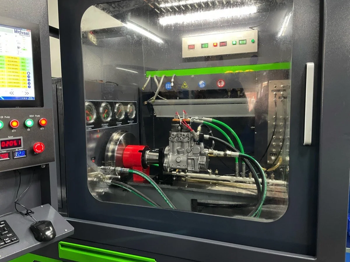 A piece of industrial machinery inside a sealed chamber with electronic controls and gauges, used for testing or manufacturing purposes.