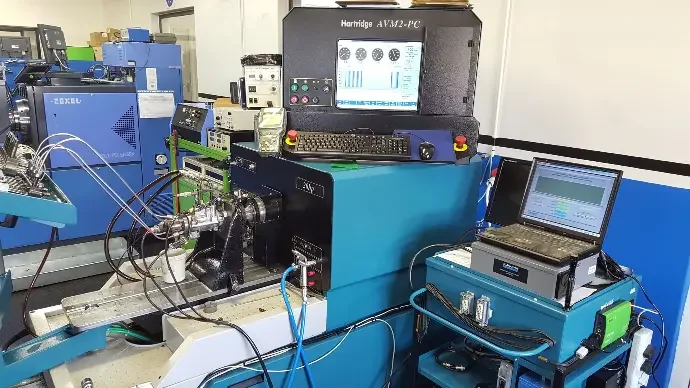 Laboratory equipment setup with a computer, testing machine, and electronic devices on a blue workstation.