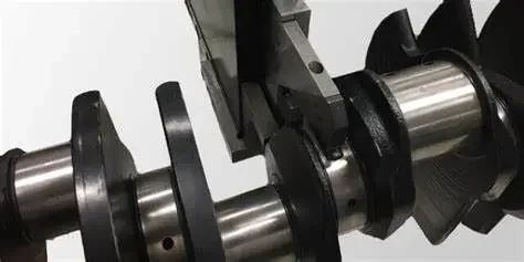 Close-up of a metal crankshaft with counterweights and connecting rods.