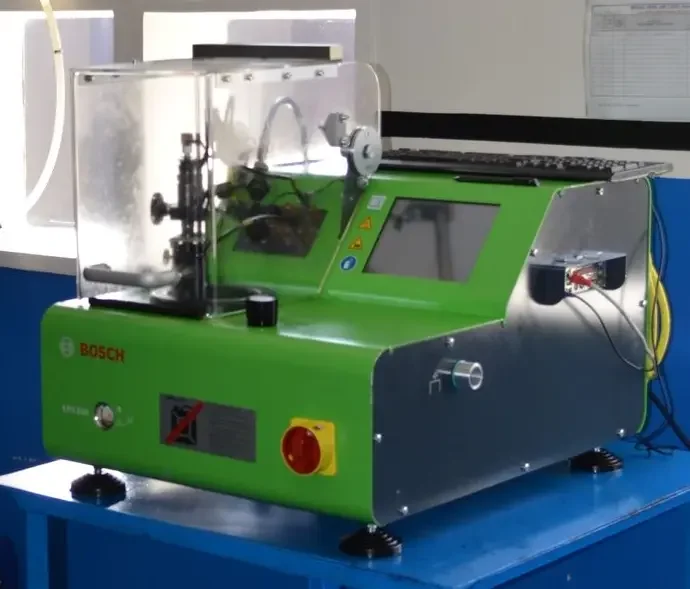 A Bosch laboratory testing machine with green and silver body, featuring a touchscreen display, safety shield, and control buttons, positioned on a blue work surface in a laboratory setting.