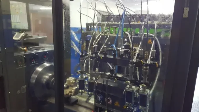 Industrial machinery with multiple metal pipes and valves inside a controlled enclosure.