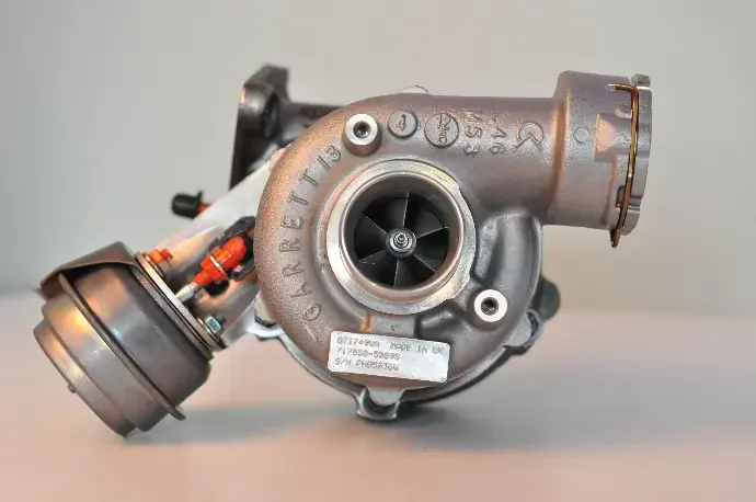 Close-up of a metallic turbocharger with visible compressor wheel and mounting details.