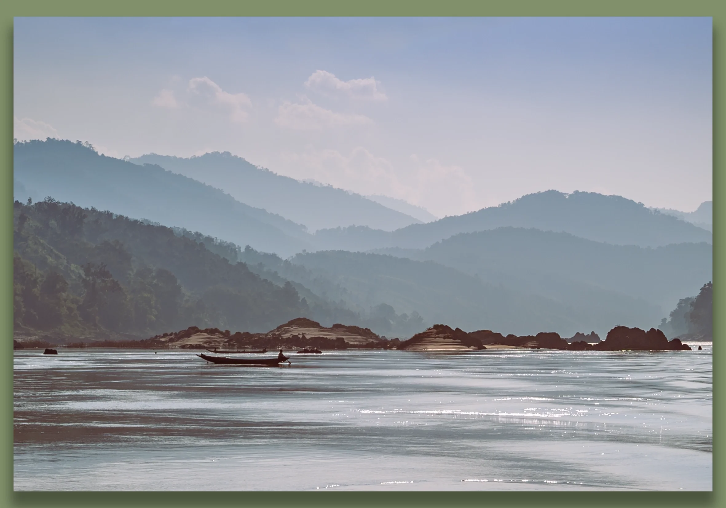 A boat on calm river waters with a mountainous landscape in the background under a partly cloudy sky.
