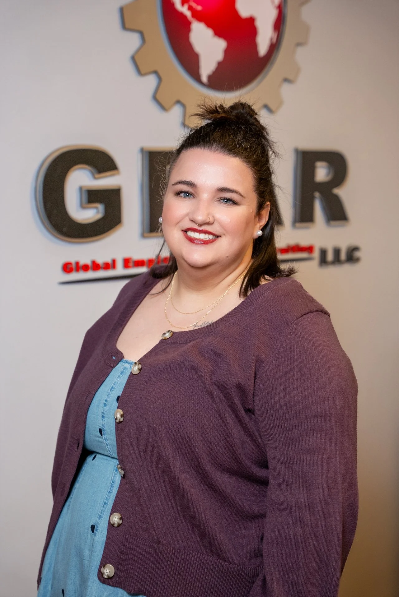 A woman smiling in front of a sign reading 'GIR' with the words 'Global Employment...' underneath, and a globe with a gear around it logo in the background.