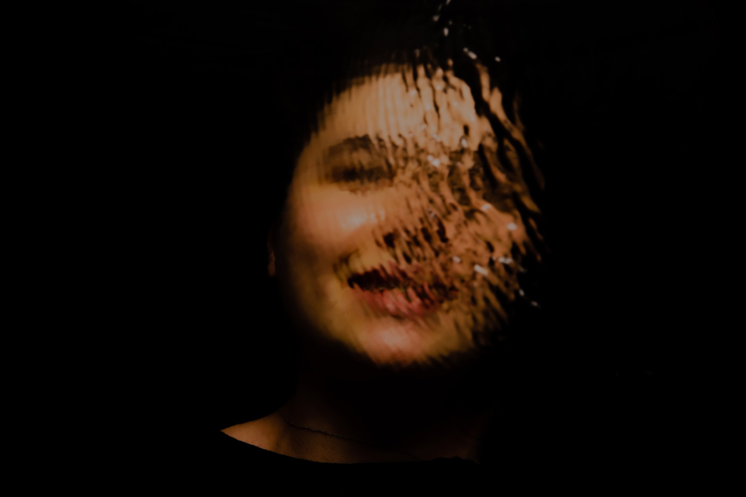 Visage d'une personne en partie obscurcie avec un motif de lumière et d'ombres sur le visage.