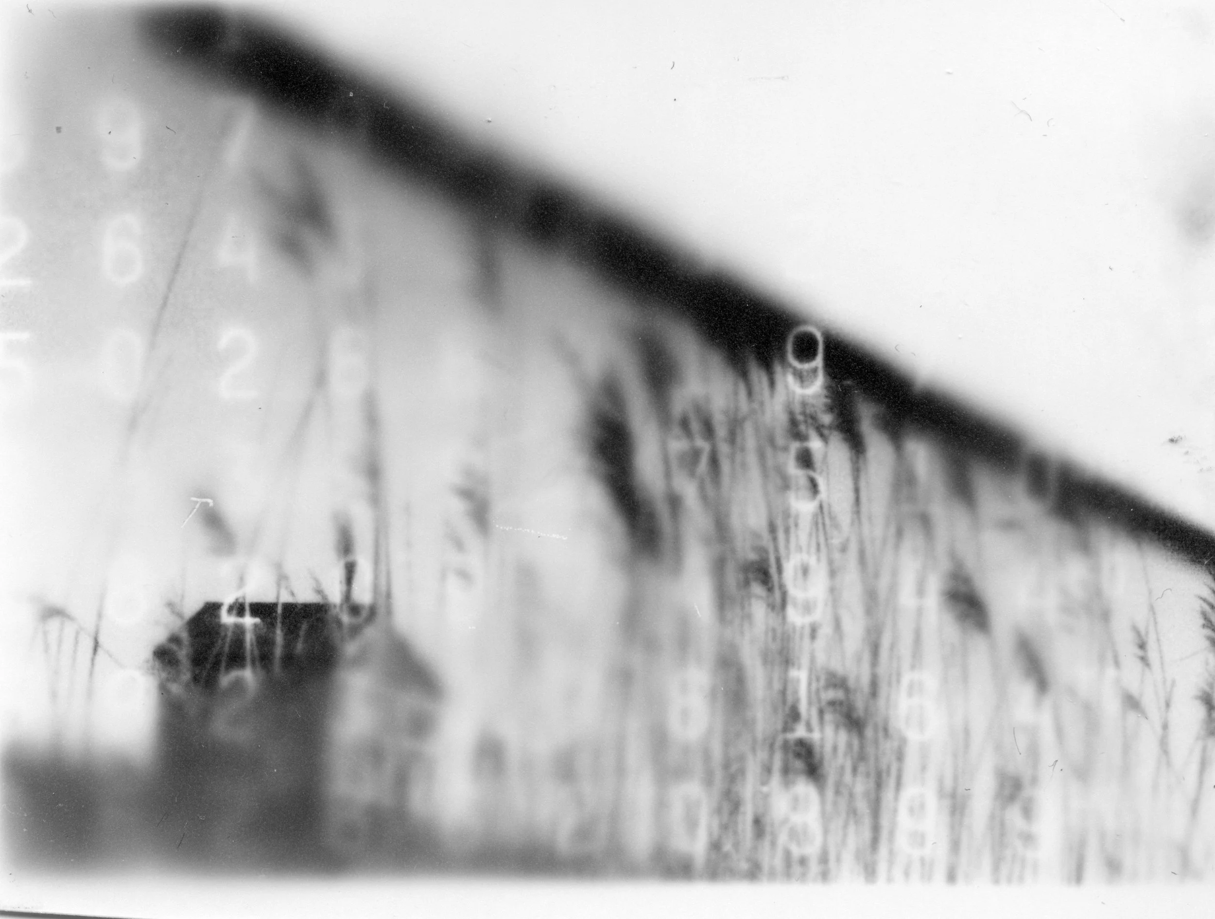 Photo en noir et blanc montrant un bâtiment avec une façade en bois et une rangée de fenêtres, légèrement flou.