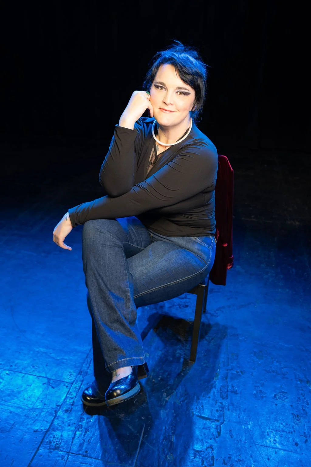 Leadership practitioner seated thoughtfully under stage lighting