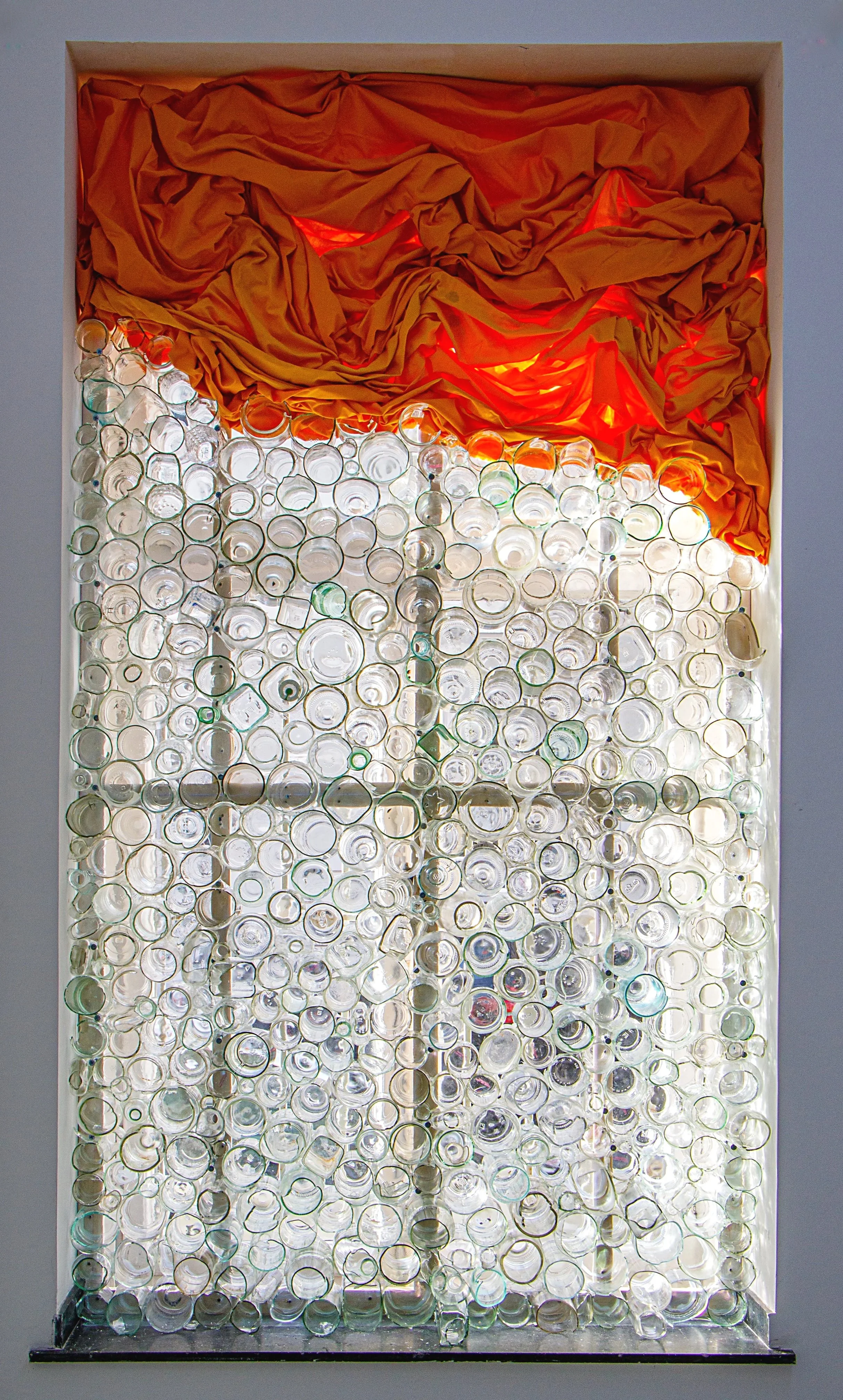 Kunstinstallation mit Glasflaschen und orangefarbenem Stoff im Rahmen einer Wand, Raum für Kunst Oberkassel des zeitgenössischen deutschen Künstlers Eduard Winklhofer 