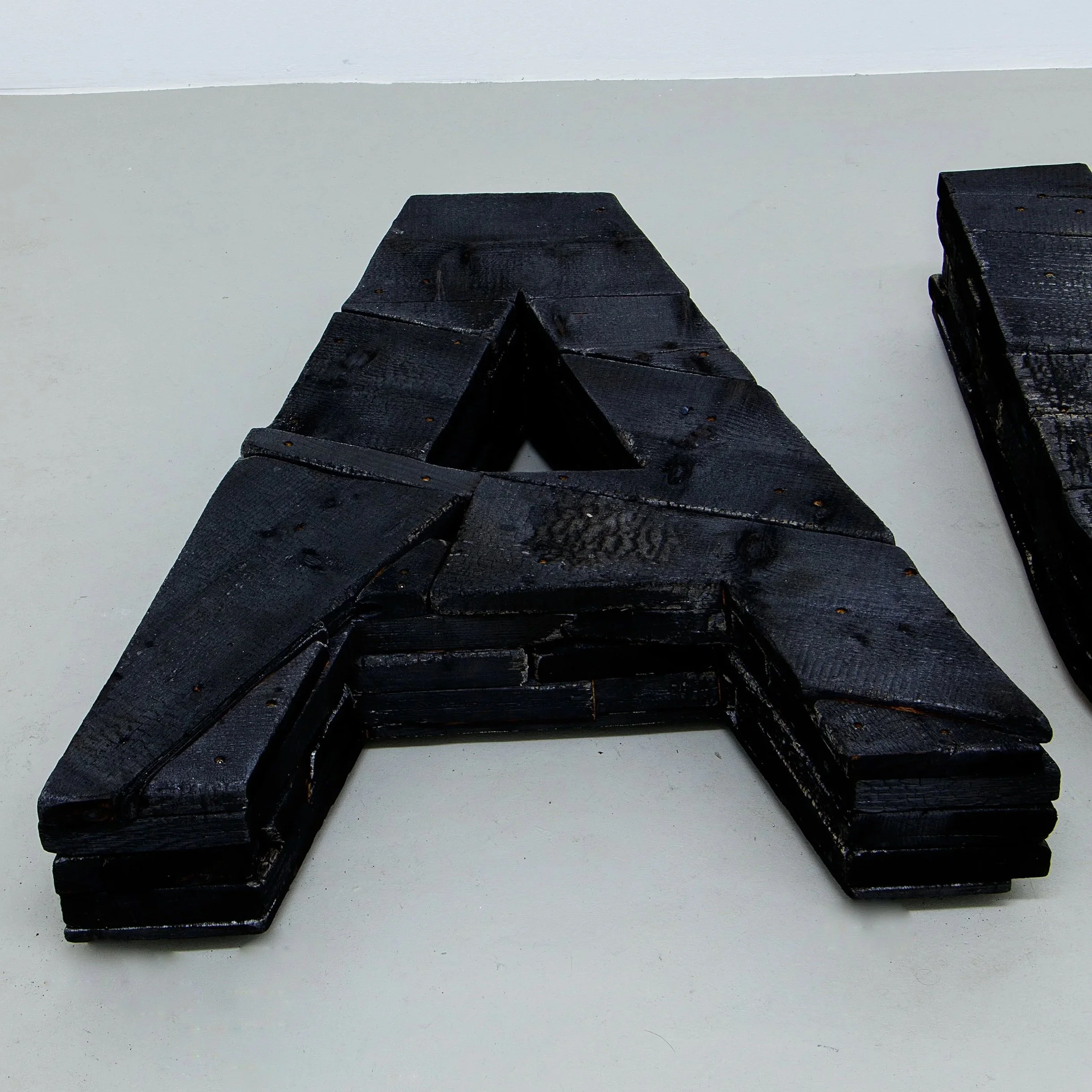 Detail, Kunstinstallation mit schwarzen Holzbuchstaben und einer Pyramide aus Glasscherben, Auge, verbranntes Holz, Glasscherben, Raum für Kunst Oberkassel des zeitgenössischen deutschen Künstlers Eduard Winklhofer