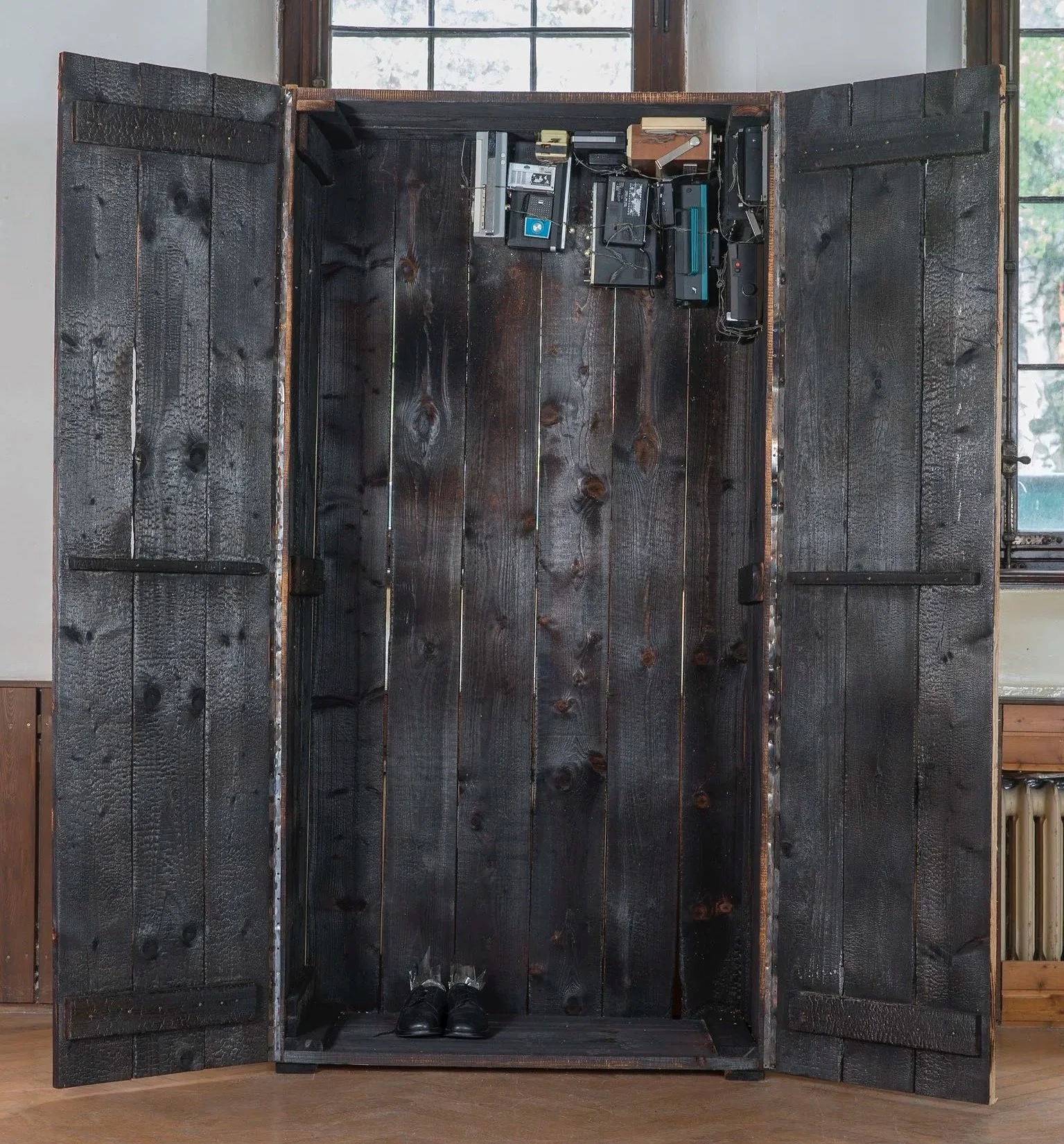 Kunstinstallation, dunkler Holzkasten mit Schuhen am Boden, im Inneren befinden sich alte, veraltete elektronische Geräte und Kabel, Eduard Winklhofer Düsseldorfer aktueller Künstler 