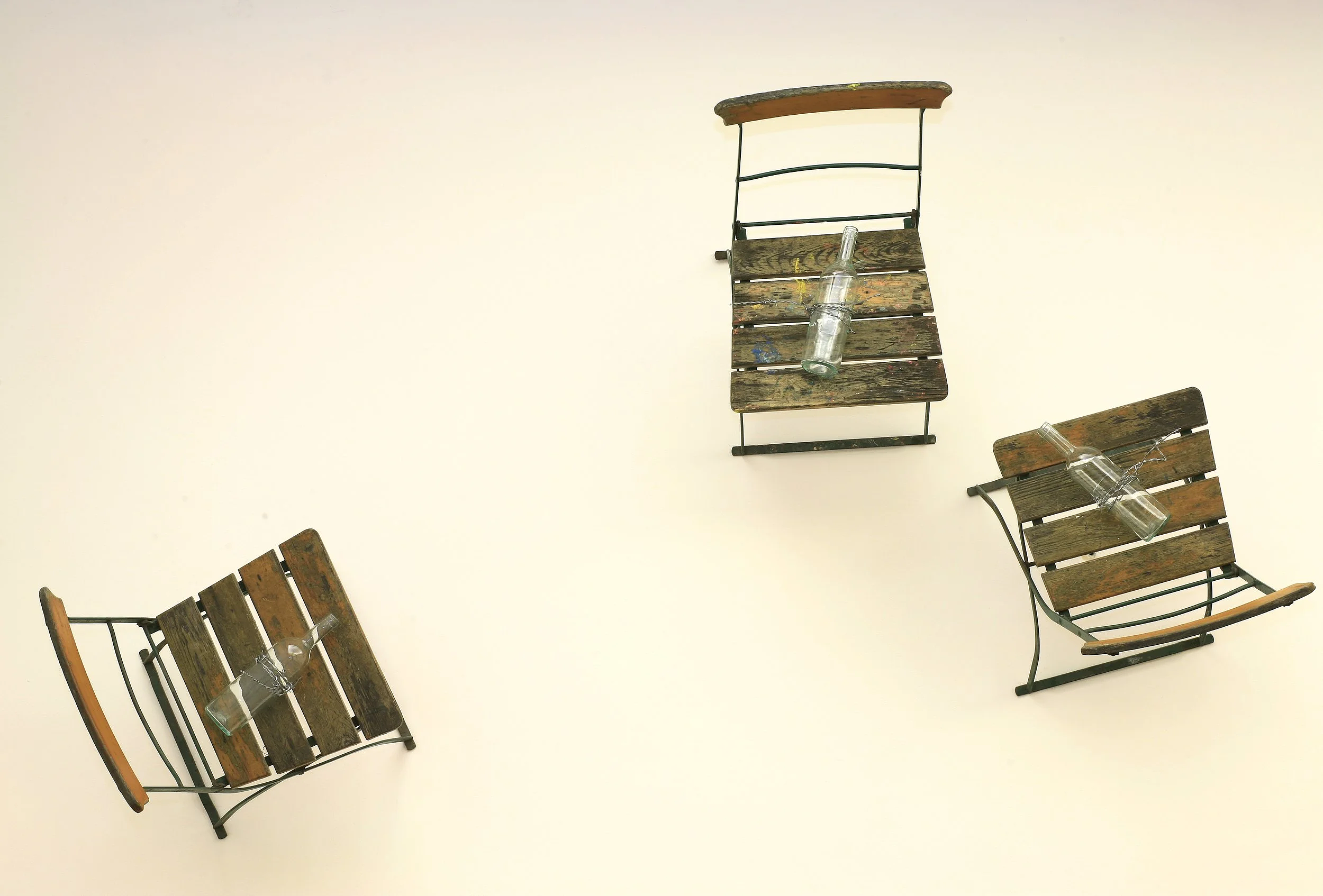 Große Installation, Stühle die durch Stacheldraht der an Flöten/Flaschen befestigt ist und durch die Wand verläuft, vertikal an dieser gehalten werden, Ausstellung vom zeitgenössischen Düsseldorfer Künstler Eduard Winklhofer, in La Spezia 90er Jahre