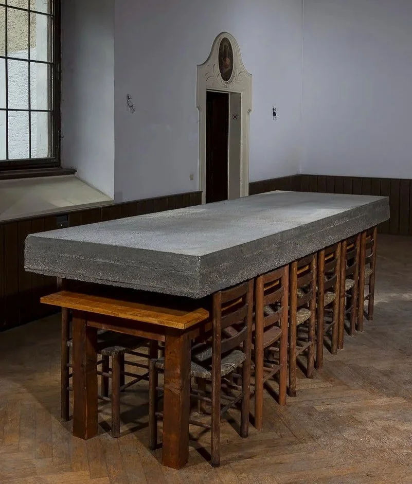Moderne Installation, Ein langer Holztisch mit einem großen Betonblock, Arbeit des österreichischen zeitgenössischen Künstlers Eduard Winklhofer, Ausstellung in Regensburg