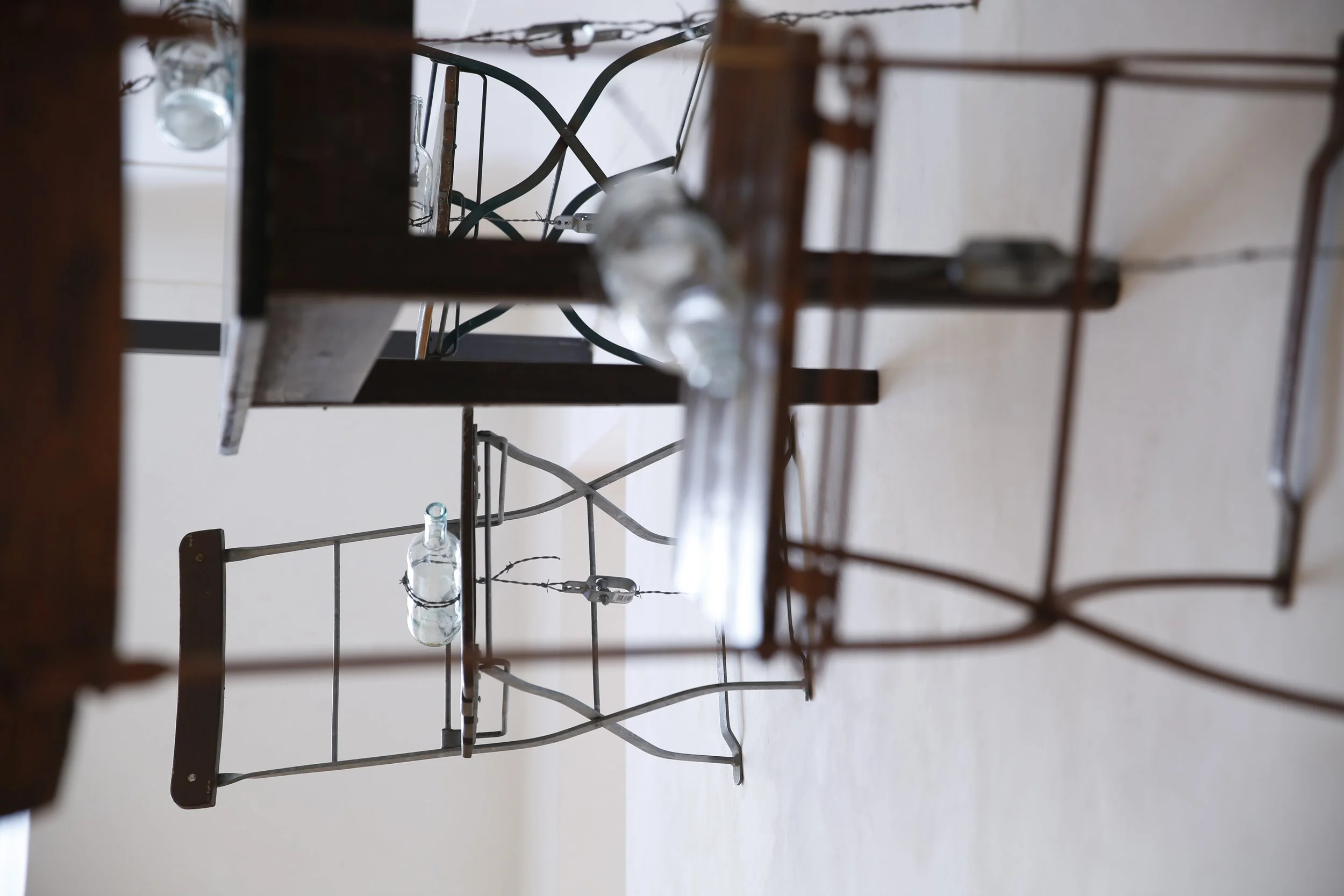 Kunstinstallation, Holzflöten und Stacheldraht halten Tische und Stühle auf der anderen Seite der Wand,  Kulturzentrum bei den Minoriten, Graz, Ausstellung des aktuellen Künstlers Eduard Winklhofer aus Düsseldorf 