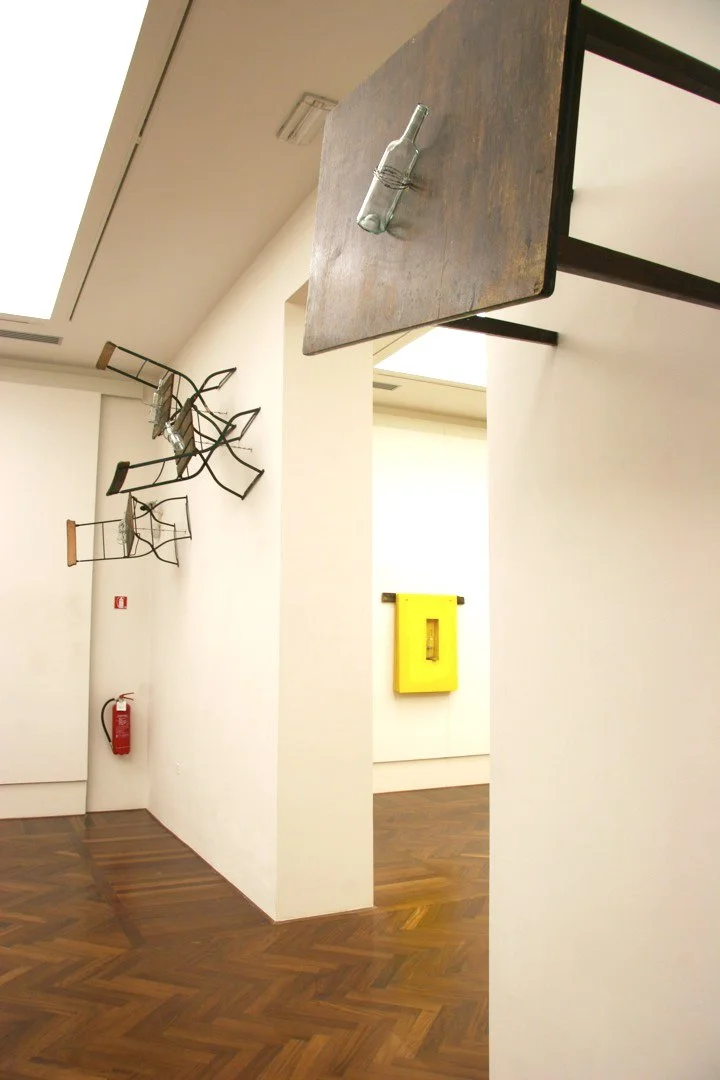 Große Installation, Tische die durch Stacheldraht der an Flöte befestigt ist und durch die Wand verläuft, vertikal an dieser gehalten werden, Ausstellung vom zeitgenössischen Düsseldorfer Künstler Eduard Winklhofer, in La Spezia 90er Jahre