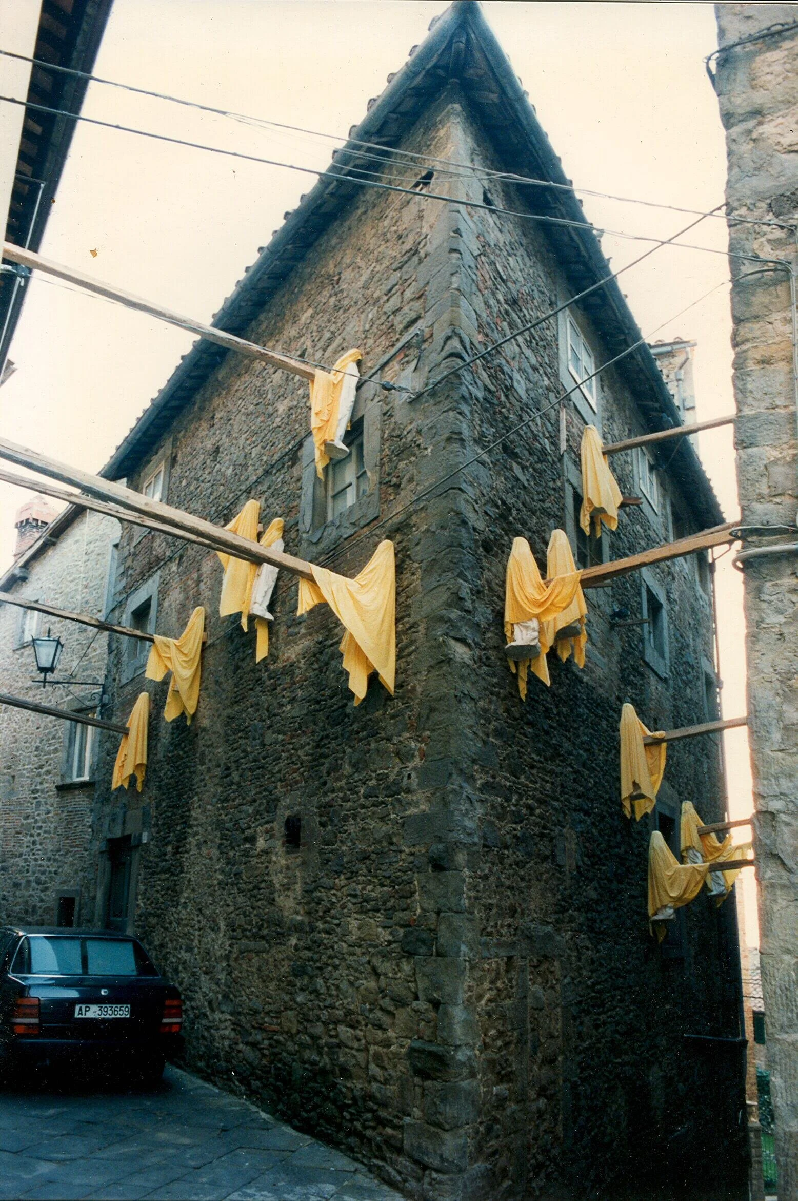 Eduard Winklhofer, zeitgenössische Kunst Düsseldorf, Künstler Atelier Düsseldorf, 1994, Installation, 13 Gips Madonnen, Gelber Stoff, Holzpfeiler, Ausstellung “Isole del disordine”, Cortona, Italien