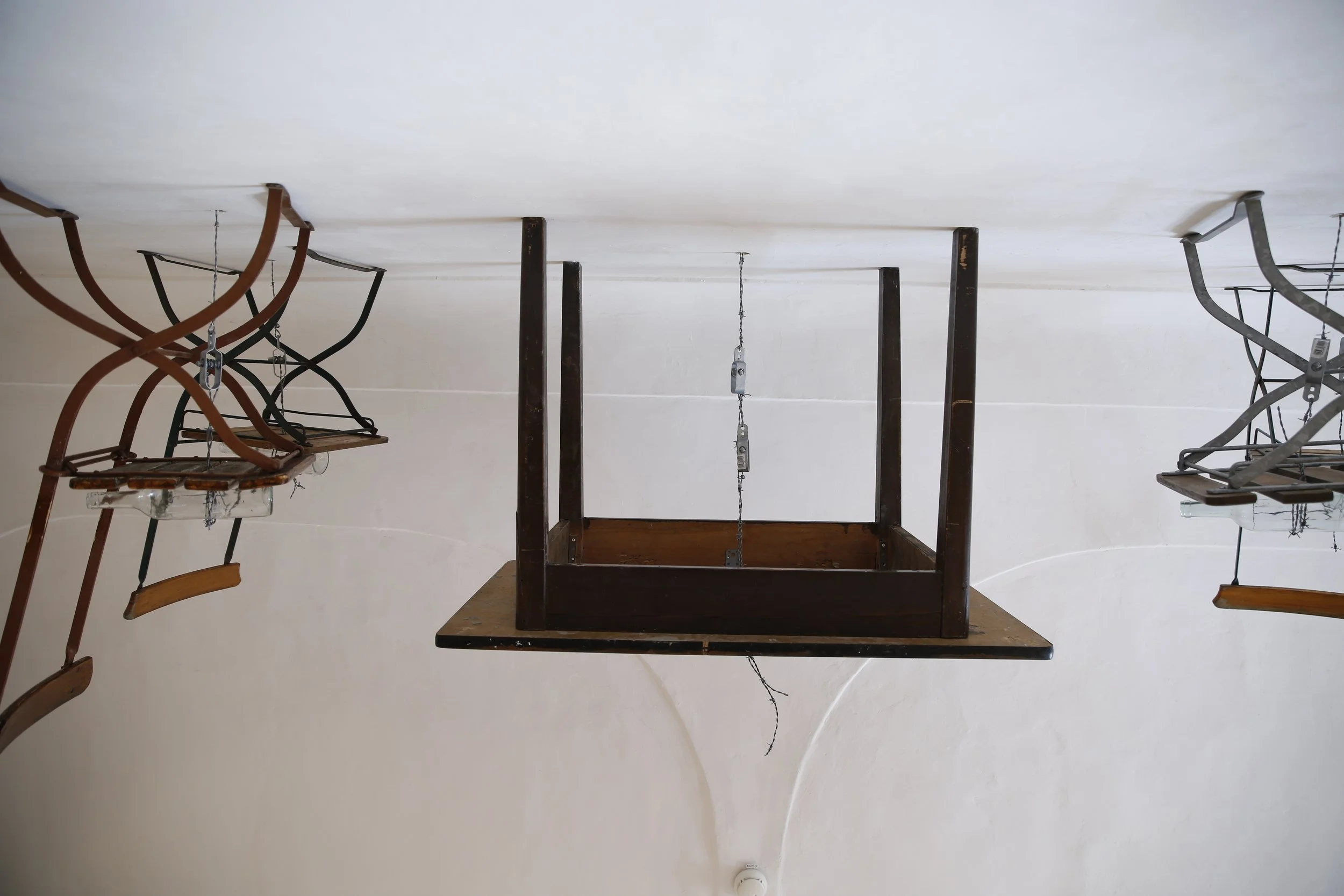 Kunstinstallation, Holzflöten und Stacheldraht halten Tische und Stühle auf der anderen Seite der Wand,  Kulturzentrum bei den Minoriten, Graz, Ausstellung des aktuellen Künstlers Eduard Winklhofer aus Düsseldorf 