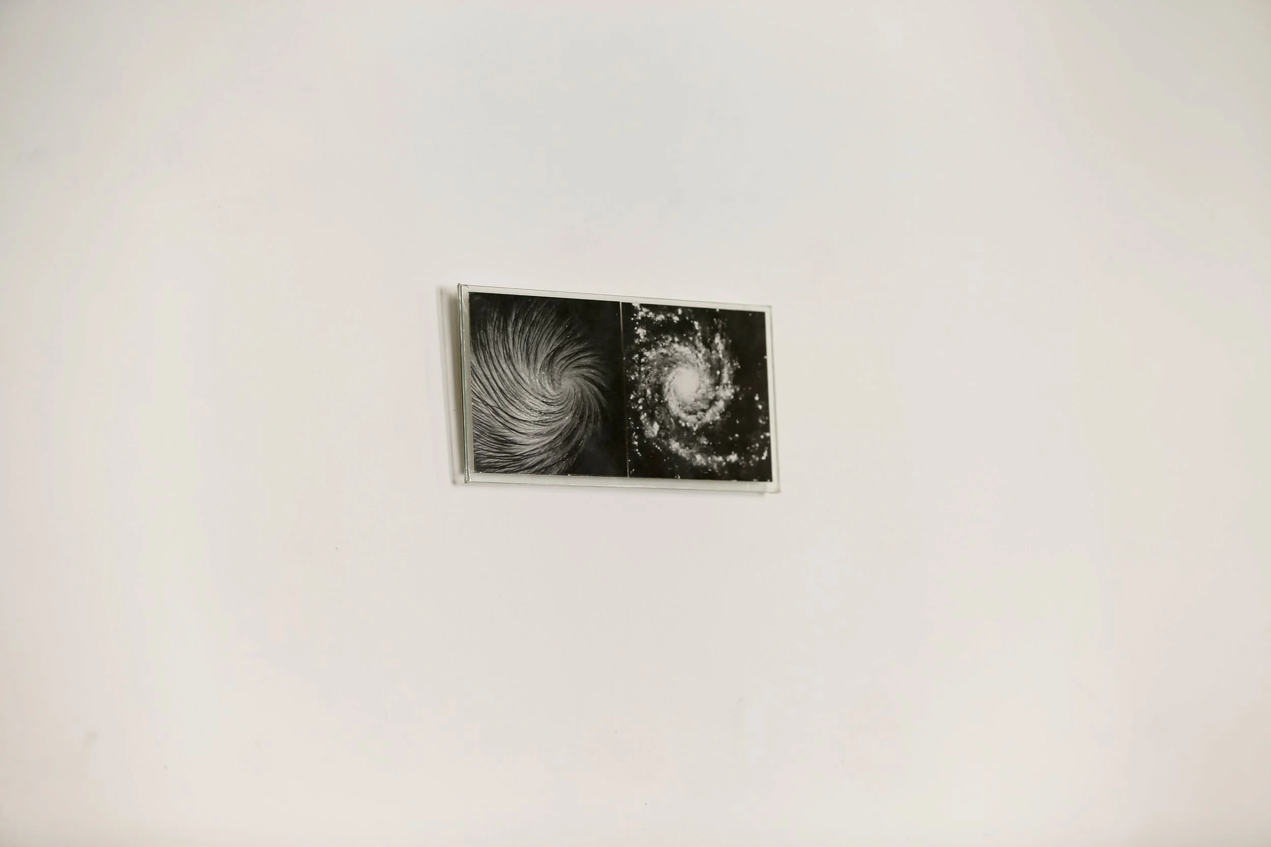 Ein gerahmtes Kunstwerk an einer weißen Wand, das zwei schwarz-weiße Bilder von Spiralgalaxien zeigt, Eduard Winklhofer, Düsseldorf Heerdt