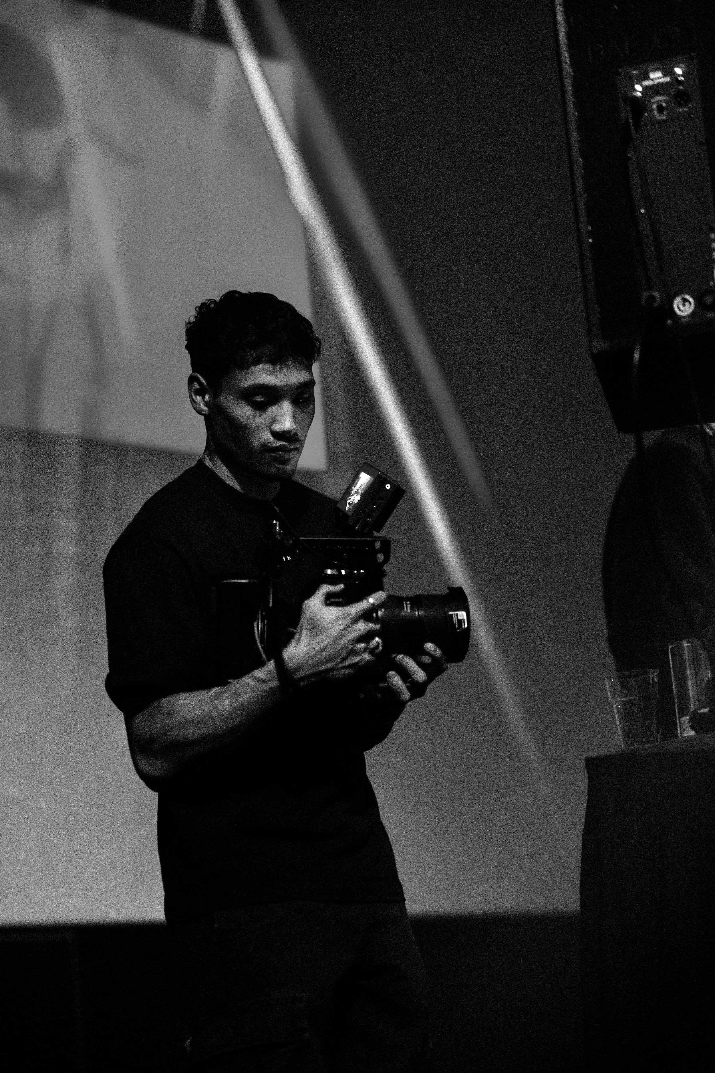 Een man met een camera in een donkere omgeving, mogelijk tijdens een evenement of fotoshoot.