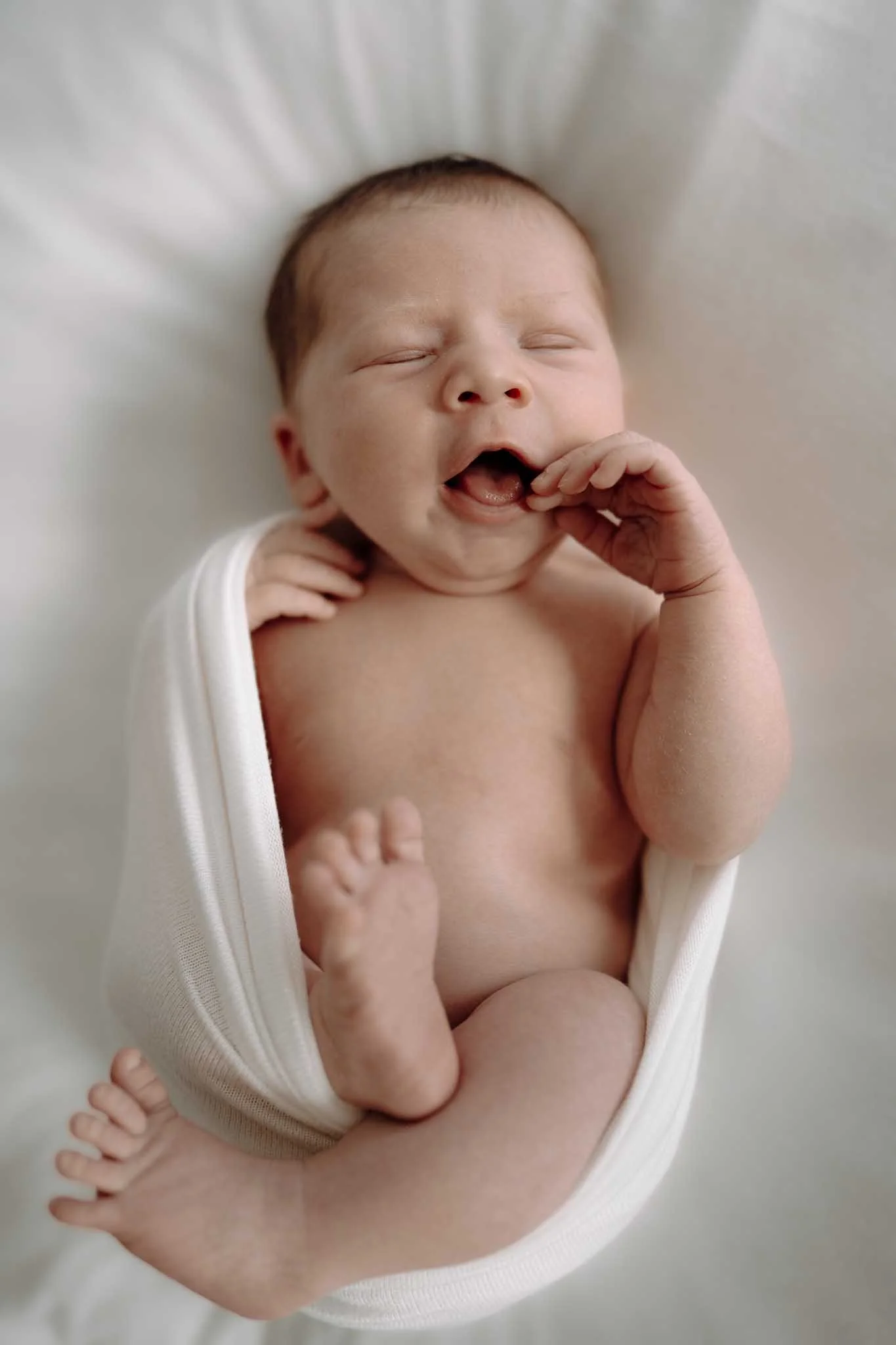 Nyfødt baby gjesper. Koser seg. 